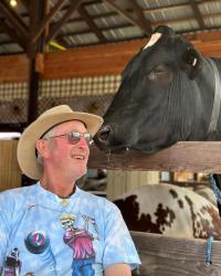 Jeffrey Pulver pictured smiling next to a black cow on his dairy farm.